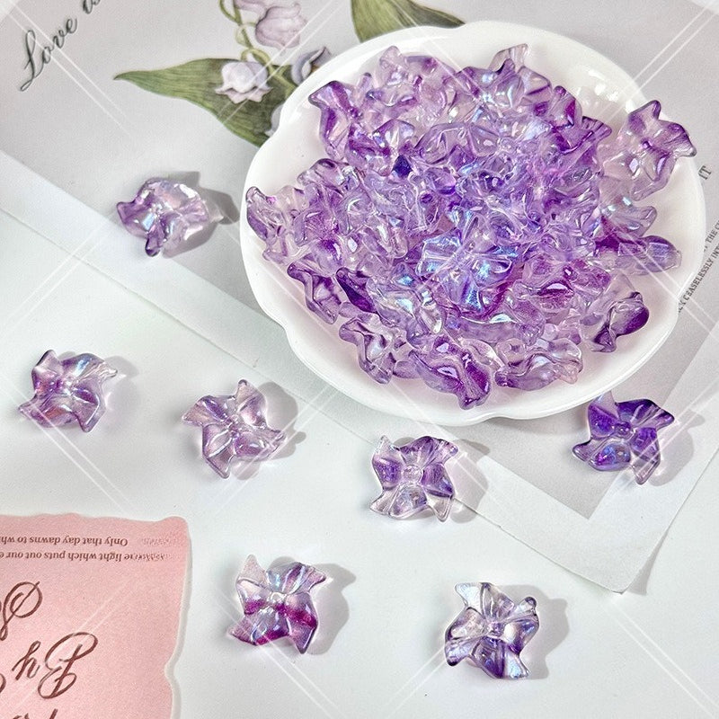Purple iridescent 20mm carved glass windmill beads in a white scalloped dish on a white background