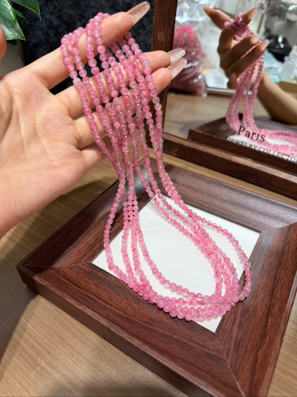 Hand holding rhodonite triple-wrap bracelet strands