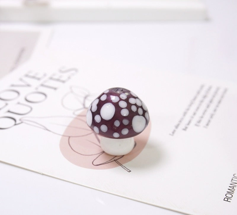 Burgundy mushroom-shaped glass bead with white spots on a LOVE QUOTES card