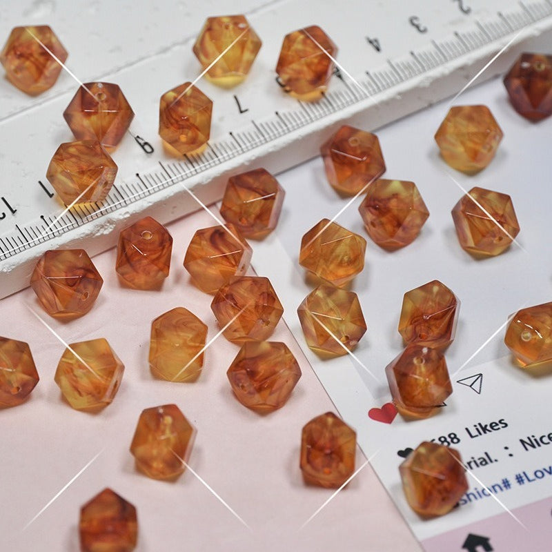 Faceted amber-orange beads scattered on a white surface with a ruler