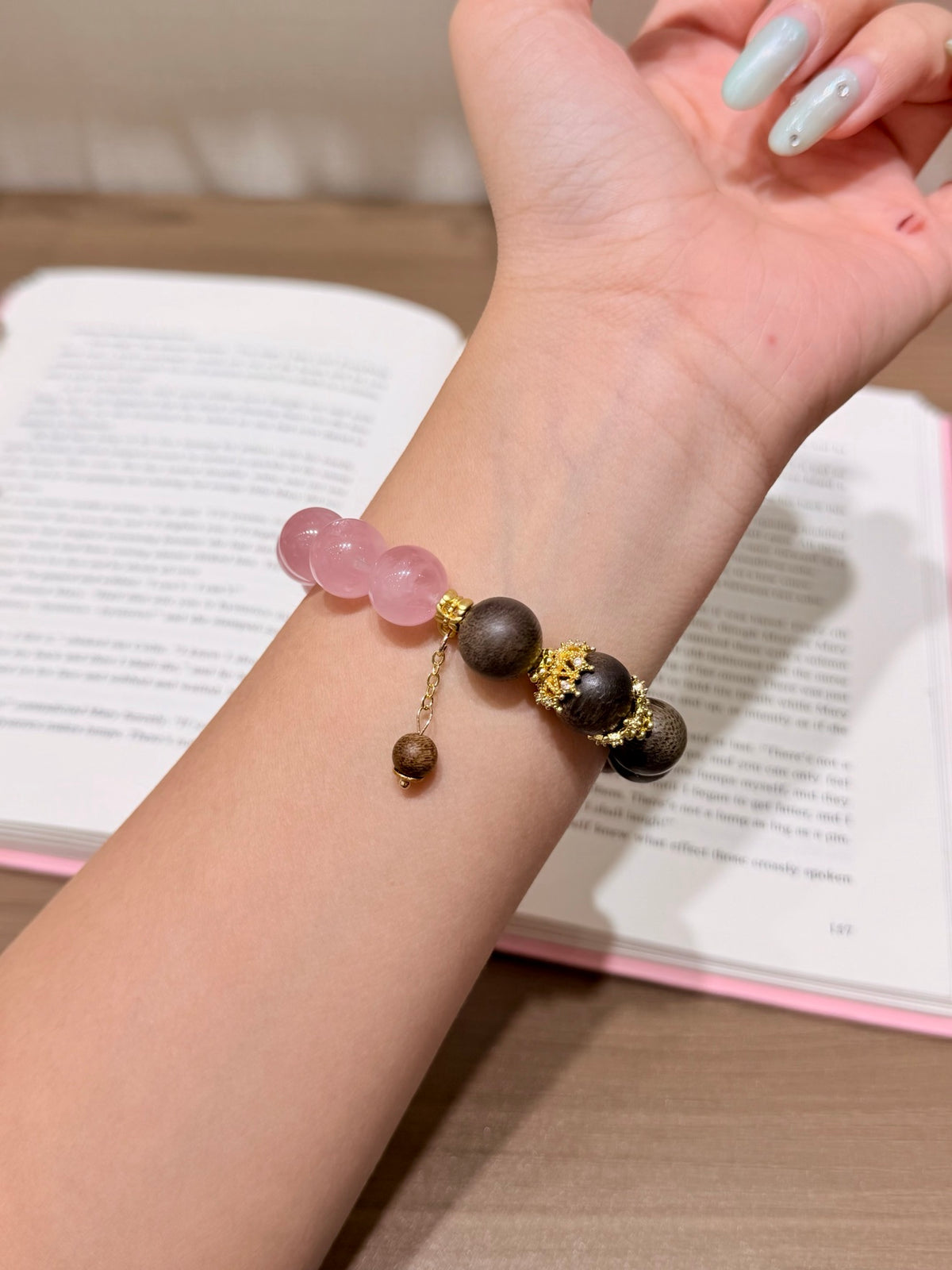 Blush pink quartz and dark sandalwood bead bracelet reflected in mirror