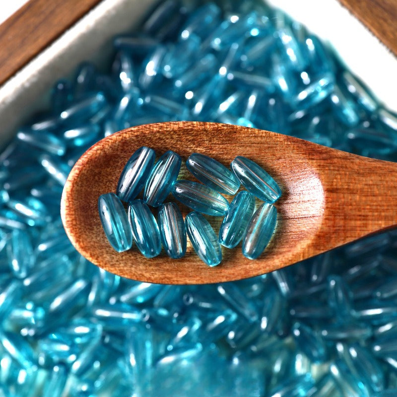 Blue translucent 4x9mm glazed glass long rice beads in a wooden spoon