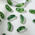 Green translucent glass beads with natural marbling, arranged on a white textured fabric background.