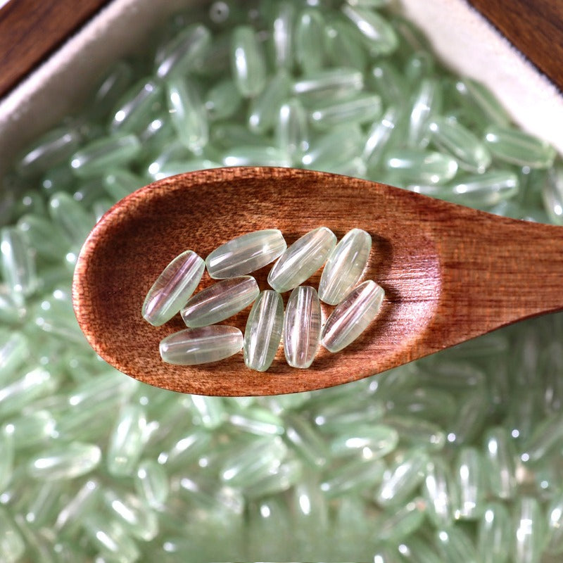 Pale green translucent 4x9mm glazed glass long rice beads in a wooden spoon
