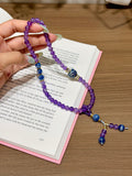 Purple amethyst double-loop bracelet with blue beads held over open book